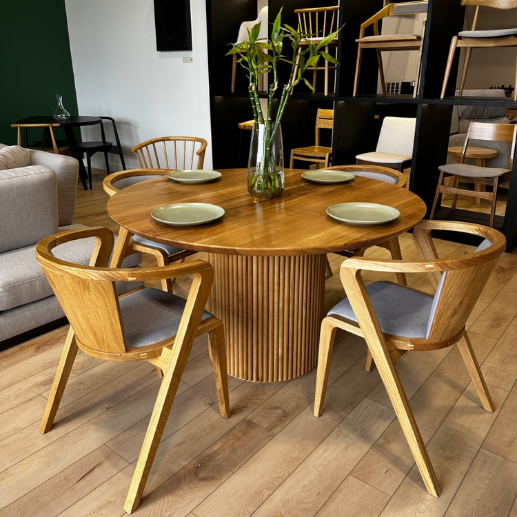 Dining area with wooden table and chairs in a room with a couch and additional furniture.