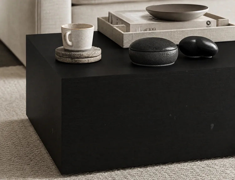 Close-up of a black coffee table corner with a ceramic cup and decorative objects
