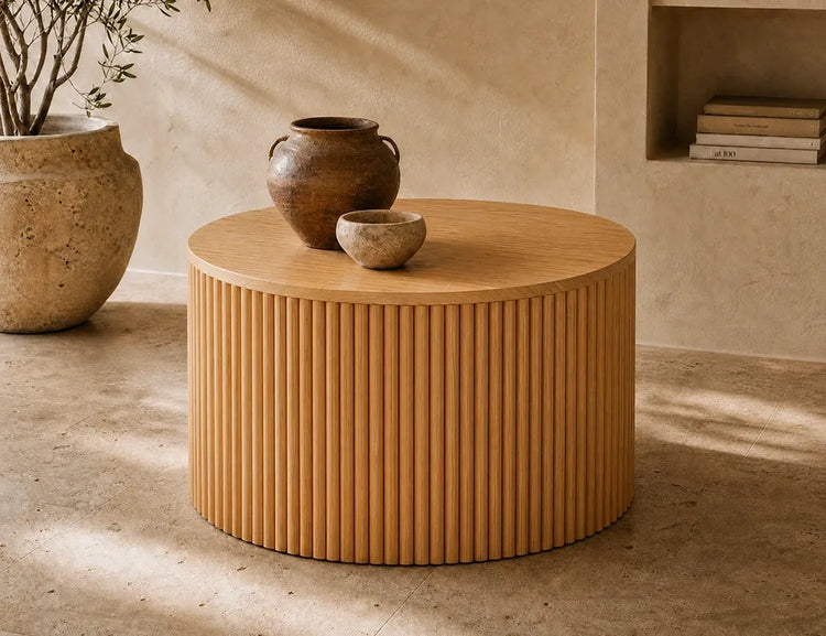 Round wood coffee table with a fluted base, topped with a ceramic vase and bowl
