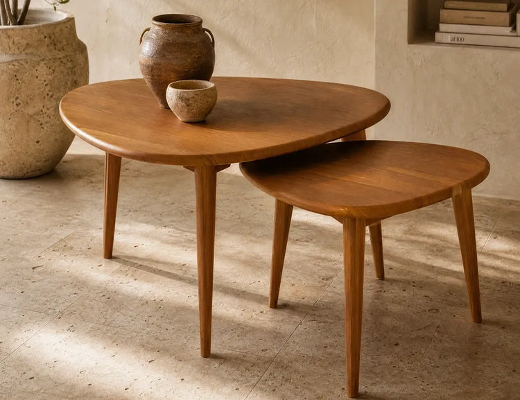Two organically shaped wood nesting coffee tables with ceramic decor on top